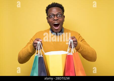 Schöner afroamerikanischer junger Mann hält Einkaufstaschen Stockfoto