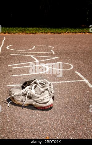 Ein Paar Laufschuhe an der Startlinie für die Schichtführung. Die Schuhe sind alt und abgenutzt. Stockfoto