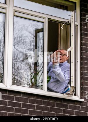 Harrogate, North Yorkshire, Großbritannien. April 2020. John Shannon, der 103 ist, kam aus seinem Fenster, um unsere NHS-Hauptarbeiter als Teil der Clap for Our Carers Initiative zu feiern. John wurde aufgrund seiner freiwilligen Arbeit in der Gemeinde, als er 101 war, mit dem Preis "Point of Light in Society" des Premierministers ausgezeichnet. Als Kriegsmarineoffizier half er, die belgische Sektion der Royal Navy zu gründen, und 2013 wurde er eingeladen, den ersten Stützpunkt der belgischen Marine zu eröffnen. Credit: ernesto rogata/Alamy Live News Stockfoto
