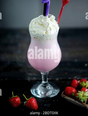Ein Glas Erdbeer-Milchshake garniert mit Schlagsahne Stockfoto