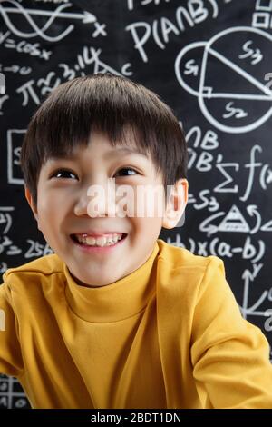 Schreiben Sie volle mathematische Probleme vor der Tafel glücklichen Jungen Stockfoto