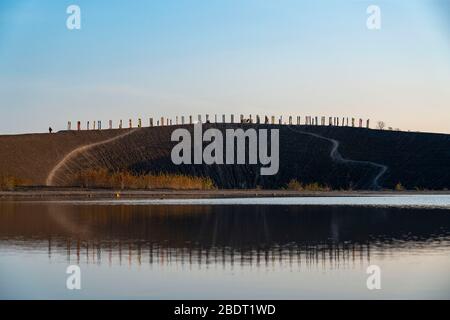 Der Schleuder Haniel, 185 Meter hoher Schlaghaufen, in der Grube Prosper Haniel, 2019 geschlossen, Kunstwerk Totems des Bildhauers Augustin Ibarrola, Sonnenuntergang Stockfoto