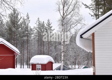 Holzhäuser über dem arktischen Kreis, bedeckt mit starkem Schnee. Der reinweiße skandinavische Winter ist der ideale Kurzurlaub für Paare und Familien mit Kindern Stockfoto