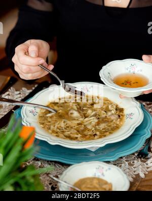Mann gießt Essig in Fleischbällensuppe mit Nudeln Stockfoto