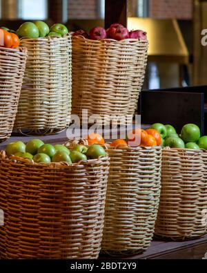 Strohfruchtkörbe gefüllt mit Äpfeln Granatäpfel und Orangen Stockfoto