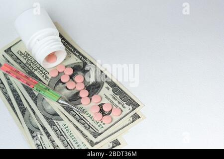 Tabletten sind in US-Dollar, ein medizinisches Thermometer verstreut. Verluste durch Behandlung und Quarantäne der COVID-19-Coronavirus-Pandemie. Kopierbereich Stockfoto