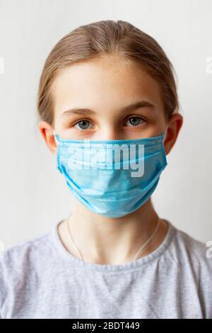 Kleines Teenager-Mädchen in medizinischen Maske traurig und erschrocken. Coronavirus Schutz, tragen Masken Konzept Stockfoto