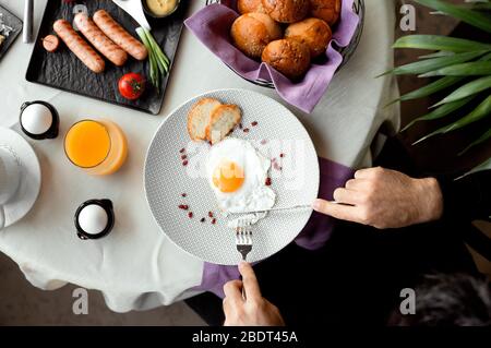 Blick von oben auf den Mann, der das Frühstück mit einem sonnigen Ei serviert Stockfoto