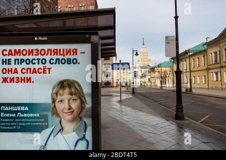 Moskau, Russland. 9. April 2020 Blick auf eine leere Straßen im Zentrum von Moskau während der Quarantäne Coronavirus-Epidemie von den städtischen Behörden auferlegt. Auf dem Spruchband mit einem Arztportrait an der Bushaltestelle steht: "Selbstisolierung ist nicht nur ein Wort. Es rettet das Leben der Menschen." Stockfoto
