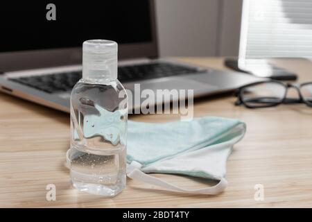 Zur Vorbeugung gegen Coronavirus befinden sich auf dem Arbeitsbereich ein Alkoholgel und eine Schutzmaske für Handdesinfektionsmittel. Gesundheitsfürsorge während der Pandemie. Stockfoto