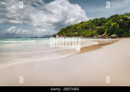 Schöner langer Sandstrand Petite Anse auf Mahe Island, Seychellen. Riesige Regenwolken am Himmel. Urlaub erholsame Ferien. Stockfoto