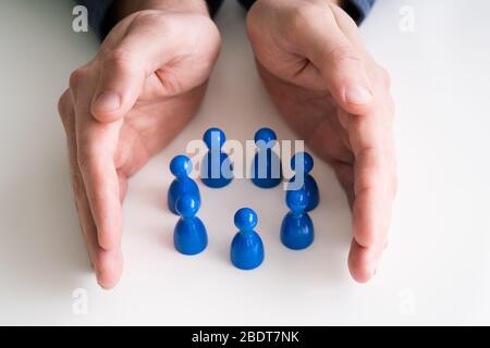 Nahaufnahme von einer Person schützende Hand bunte Steine bilden Kreis auf weißem Schreibtisch Stockfoto