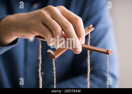 Nahaufnahme der Hand manipulieren Marionette einer Person mit String auf grauem Hintergrund Stockfoto