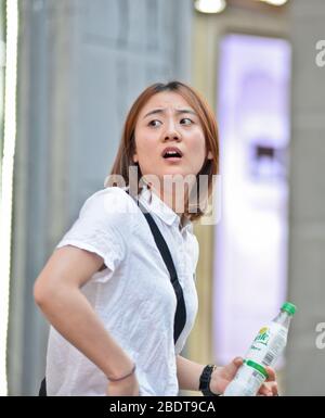 Chinesische junge Frau, die verwirrt in der Jianghan Straße, Wuhan, China, aussahen Stockfoto