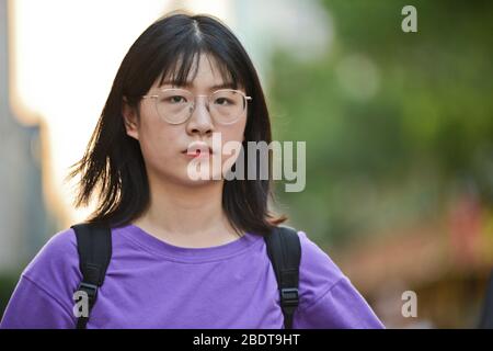 Chinesische junge Frau, die ernsthaft in der Jianghan Road, Wuhan, China aussieht Stockfoto