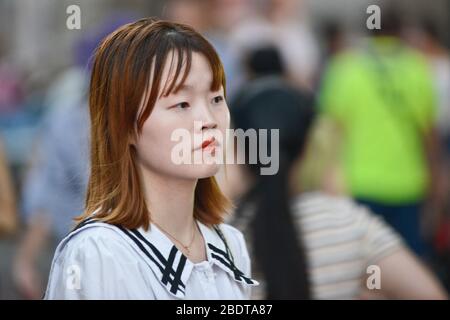 Chinesische junge Frau, die ernsthaft in der Jianghan Road, Wuhan, China aussieht Stockfoto