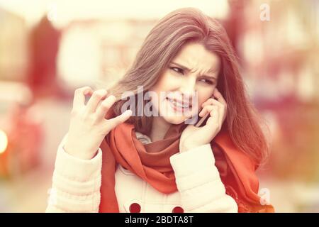 Frau telefoniert. Closeup junge unglückliche frustrierte enttäuschte schöne Frau Mädchen Dame im Gespräch auf dem Handy isolierte Stadtbild im Freien Bac Stockfoto