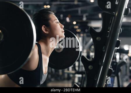 Eine junge Frau im Fitnessstudio übt eine Langhantel Stockfoto