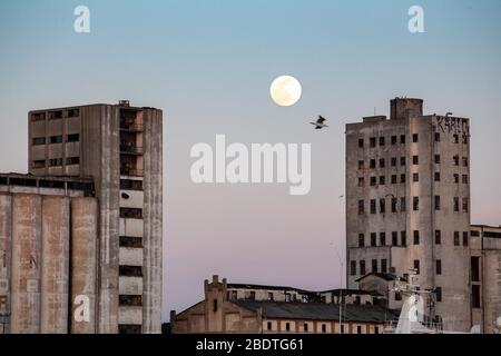 April 2020: Supermoon hellt den Himmel von Istanbul am 7. April 2020 auf. Ein Supermond ist ein Vollmond, der fast mit der nächsten Entfernung übereinstimmt, die der Mond in seiner elliptischen Umlaufbahn zur Erde erreicht, was zu einer größeren als üblichen sichtbaren Größe der Mondscheibe führt, wie sie von der Erde aus gesehen wird. Im Vordergrund steht ein verlassenes Gebäude in der Nähe von Kadikoy Haydarpasa. Credit: Tolga Ildun/ZUMA Wire/Alamy Live News Stockfoto