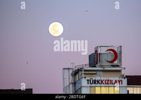 April 2020: Supermoon hellt den Himmel von Istanbul am 7. April 2020 auf. Ein Supermond ist ein Vollmond, der fast mit der nächsten Entfernung übereinstimmt, die der Mond in seiner elliptischen Umlaufbahn zur Erde erreicht, was zu einer größeren als üblichen sichtbaren Größe der Mondscheibe führt, wie sie von der Erde aus gesehen wird. Red Crescent Building im Vordergrund, Kadikoy. Der Türkische Rote Halbmond ist die größte humanitäre Organisation der Türkei und Teil der Internationalen Rotkreuz- und Rothalbmond-Bewegung. Credit: Tolga Ildun/ZUMA Wire/Alamy Live News Stockfoto