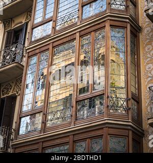 Fensterfassade im Modernista-Stil in Barcelona Spanien, mit Spiegelung der Gebäude gegenüber. Stockfoto