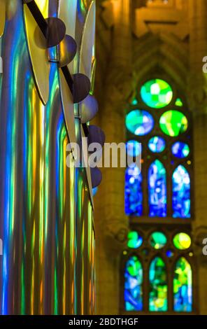 Farbiges Licht aus einem Buntglasfenster, das sich in den Orgelpfeifen der Basilika Sagrada Familia in Barcelona, Spanien, widerspiegelt. Stockfoto