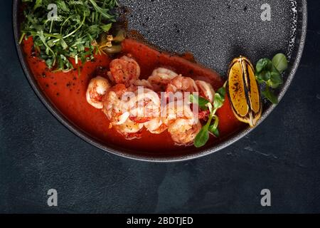 Gegrillte Tiger Cracker schön auf einem Teller mit Tomatensauce und Rucola, mediterrane Food-Konzept, Food-Foto. Draufsicht, blauer Hintergrund Stockfoto