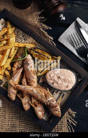 Konzept für Fisch und Pommes, traditionelles englisches Essen, frittierter Fisch und Pommes Frites. Dunkler Hintergrund, rustikal, Holzhintergrund, Kopierbereich. Ansicht von oben Stockfoto