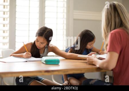 Mutter Hilft Ihren Töchtern Bei Ihren Hausaufgaben Stockfoto