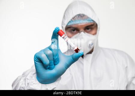 Mann Schutzkleidung Gefahrgut hält Reagenzglas gefüllt mit Blut isoliert auf einem weißen Hintergrund. Stockfoto