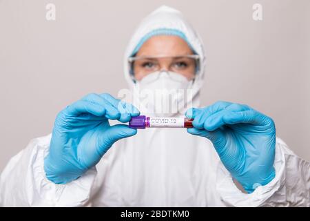 Weiblicher Arzt oder Krankenschwester im Schutzanzug mit negativem Bluttestergebnis für Coronavirus oder Kovid-19. Stockfoto