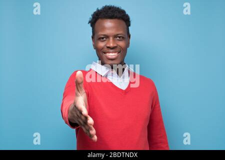 Junger afroamerikanischer Mann streckend in Richtung Kamera, um zu schütteln Hände Stockfoto