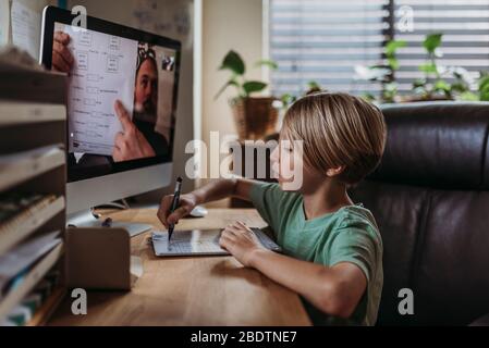 Seitenansicht des schulpflichtigen Jungen, der von einem Lehrer lernt, der die Klasse leitet Stockfoto