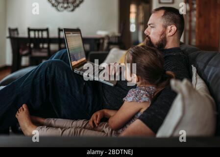 Vater arbeitet von zu Hause mit jungen Tochter während der Isolation Stockfoto