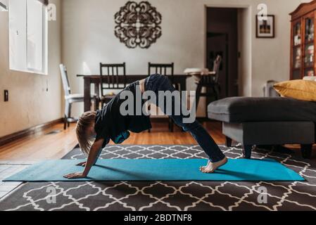 Schüler-Alter Junge, der Yoga im Wohnzimmer während der Isolation macht Stockfoto