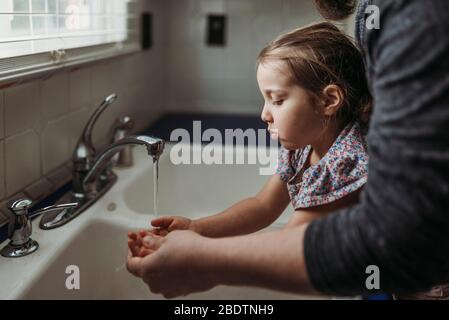 Seitenansicht von jungen Mädchen mit Händen von Papa gewaschen Stockfoto