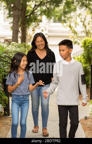 Asiatische Mutter lächelt und umarmt ihre Kinder. Stockfoto