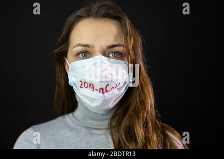 Porträt einer Frau Angst vor Coronavirus in medizinischer Maske mit 2019-ncov geschrieben Stockfoto