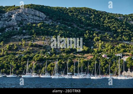 Ist eine Menge Segelboote in Marina in Kroatien bei Sonnenuntergang, Insel mit grünen Bäumen sind auf dem Hintergrund, ist in der Nähe der Stadt Vis Stockfoto