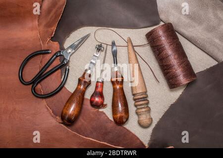 Tools für Leder basteln und Stücke von braunem Leder. Herstellung von Lederwaren. Ansicht von oben Stockfoto