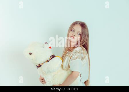 Nahaufnahme Porträt eines niedlichen verärgert traurig gelangweilten Mädchen, das Teddybär auf isolierten weißen grünen Hintergrund hält. Stockfoto