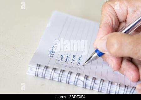 Ein Mann, der mit einem Stift eine Einkaufsliste auf einem Notizblock ausreitet Stockfoto