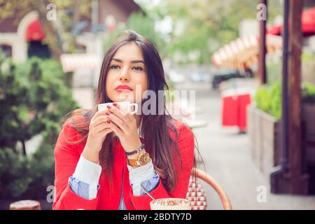 Geschäftsfrau trinken Kaffee genießen, Tee halten Heißgetränk mit Kaffeebremse in einem schicken Café, Terrasse, Balkon. Micx Rasse, arabisch Stockfoto