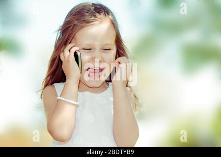 Mädchen am Telefon. Schöne aufgeregt überrascht kleines Mädchen mit Gespräch mit Freunden Handy im Freien isoliert Hintergrund positive Mensch Stockfoto