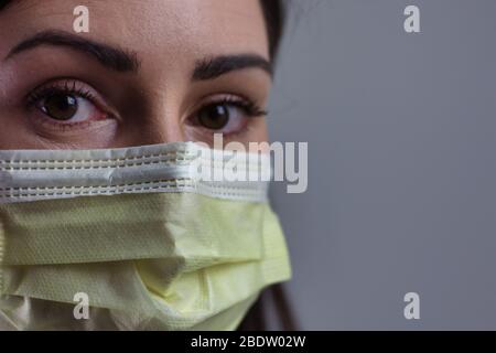 Weibliche Gesundheitsarbeiterin trägt Maske isoliert auf grauem Hintergrund. Platz für Text oder Text. Tragen Stethoskop und weißen Mantel. Stockfoto
