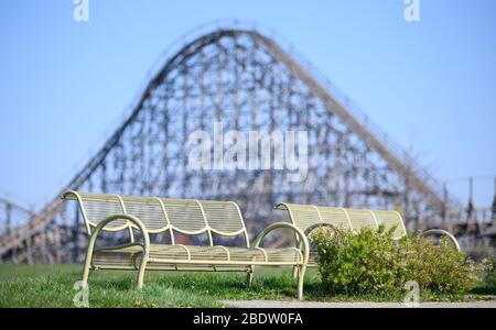 Cleebronn, Deutschland. April 2020. Leere Bänke stehen vor der hölzernen Achterbahn 'Mammut' im leeren Freizeitpark Tripsdrill. Während der osterferien ist der Park eigentlich sehr gut besucht. Um die Ausbreitung des Coronavirus zu verlangsamen, sind auch Vergnügungsparks geschlossen. Quelle: Sebastian Gollnow/dpa/Alamy Live News Stockfoto