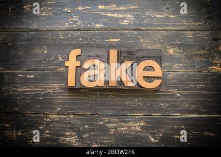 Das Wort 'FAKE' in Vintage Holz Buchdruck geschrieben auf einem Vintage rustikalen Hintergrund. Stockfoto