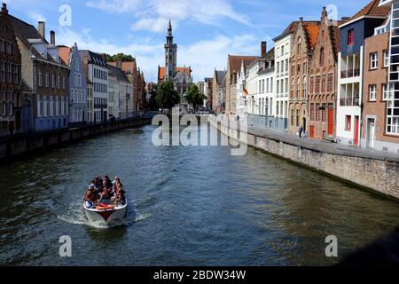 Tour Boot im Spiegelrei Kanal mit Jan Van Eyckplein Platz und dem Turm von Poortersloge (Burghers' Lodge) im Hintergrund.Brügge.Westflandern.Belgien Stockfoto