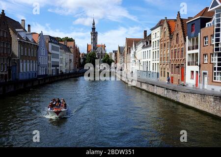 Tour Boot im Spiegelrei Kanal mit Jan Van Eyckplein Platz und dem Turm von Poortersloge (Burghers' Lodge) im Hintergrund.Brügge.Westflandern.Belgien Stockfoto