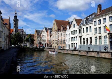 Tour Boot im Spiegelrei Kanal mit Jan Van Eyckplein Platz und dem Turm von Poortersloge (Burghers' Lodge) im Hintergrund.Brügge.Westflandern.Belgien Stockfoto